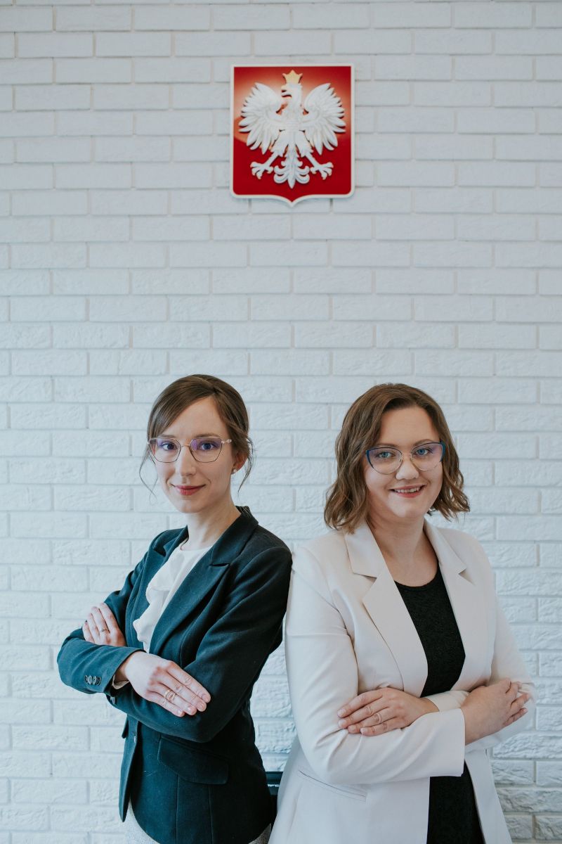 Adwokat Judyta Ciesielska i adwokat Katarzyna Markiewicz. W tle godło Polski